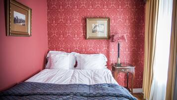 A neatly made bed with white linens, a blue patterned bedspread, and a framed picture on the wall.