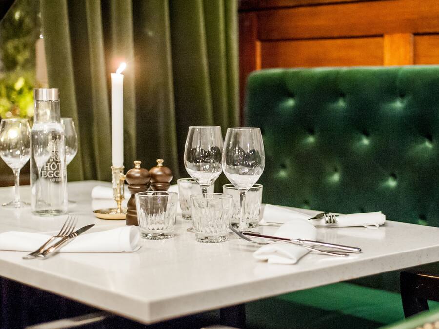 A table set for dining with clear glassware, a candle, and salt and pepper shakers.