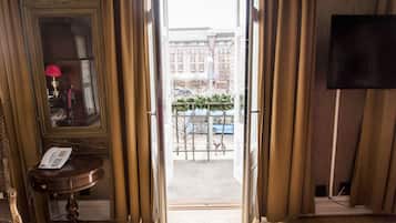 An open door leading to a balcony with a view of buildings and a parked car.