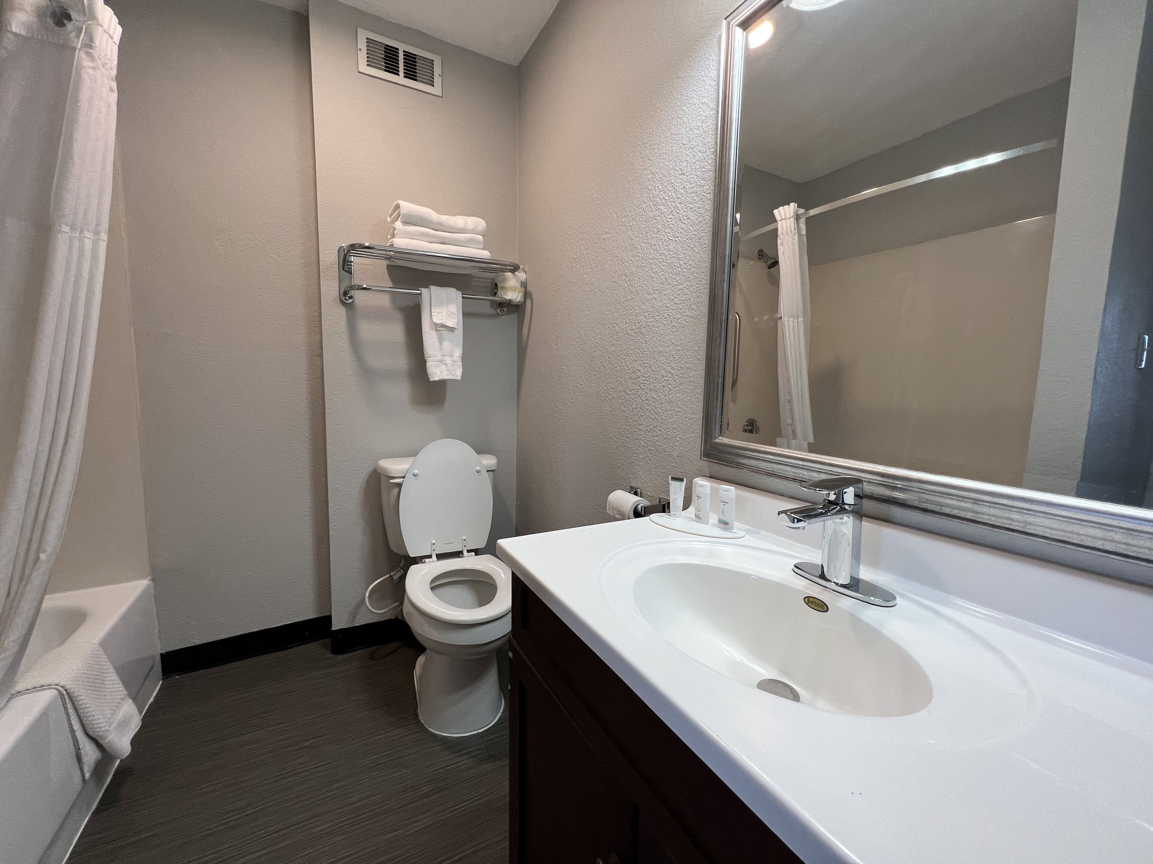A bathroom with a white toilet, a sink with a mirror, and a shower curtain.