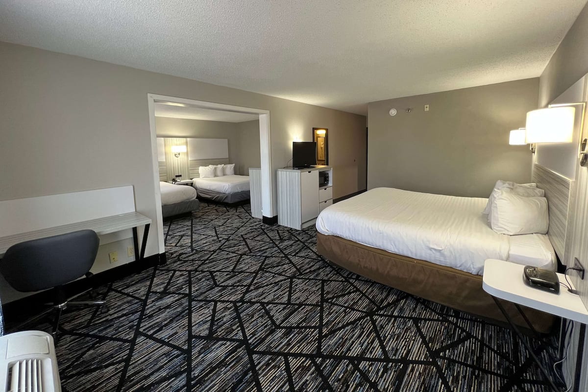 Een hotelkamer met een groot bed, een bureau met een stoel, een televisie en een spiegel.