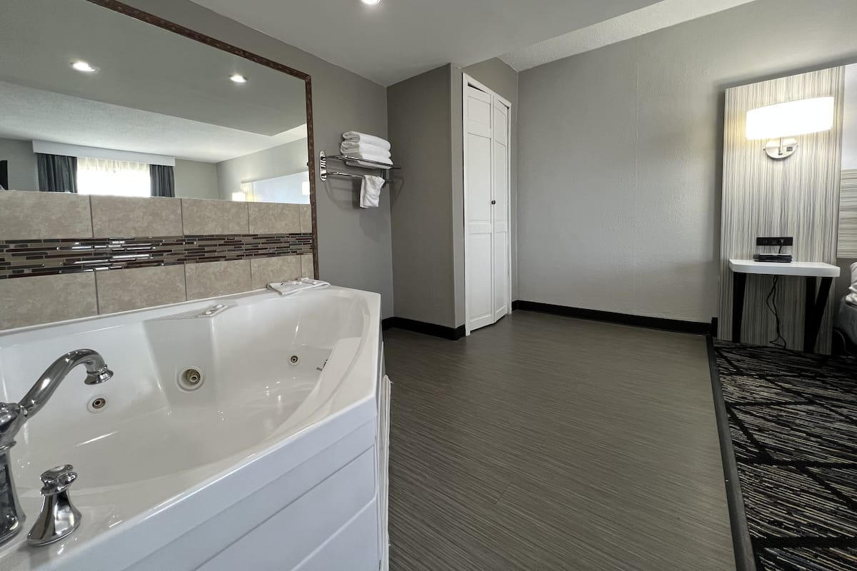 Een moderne badkamer met een ruime badkuip, een spiegel en een handdoekhouder.