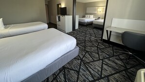 Una habitación de hotel con dos camas individuales, un escritorio, una silla, un armario y un espejo.