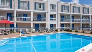 Un hotel con piscina, varios balcones y puertas azules.