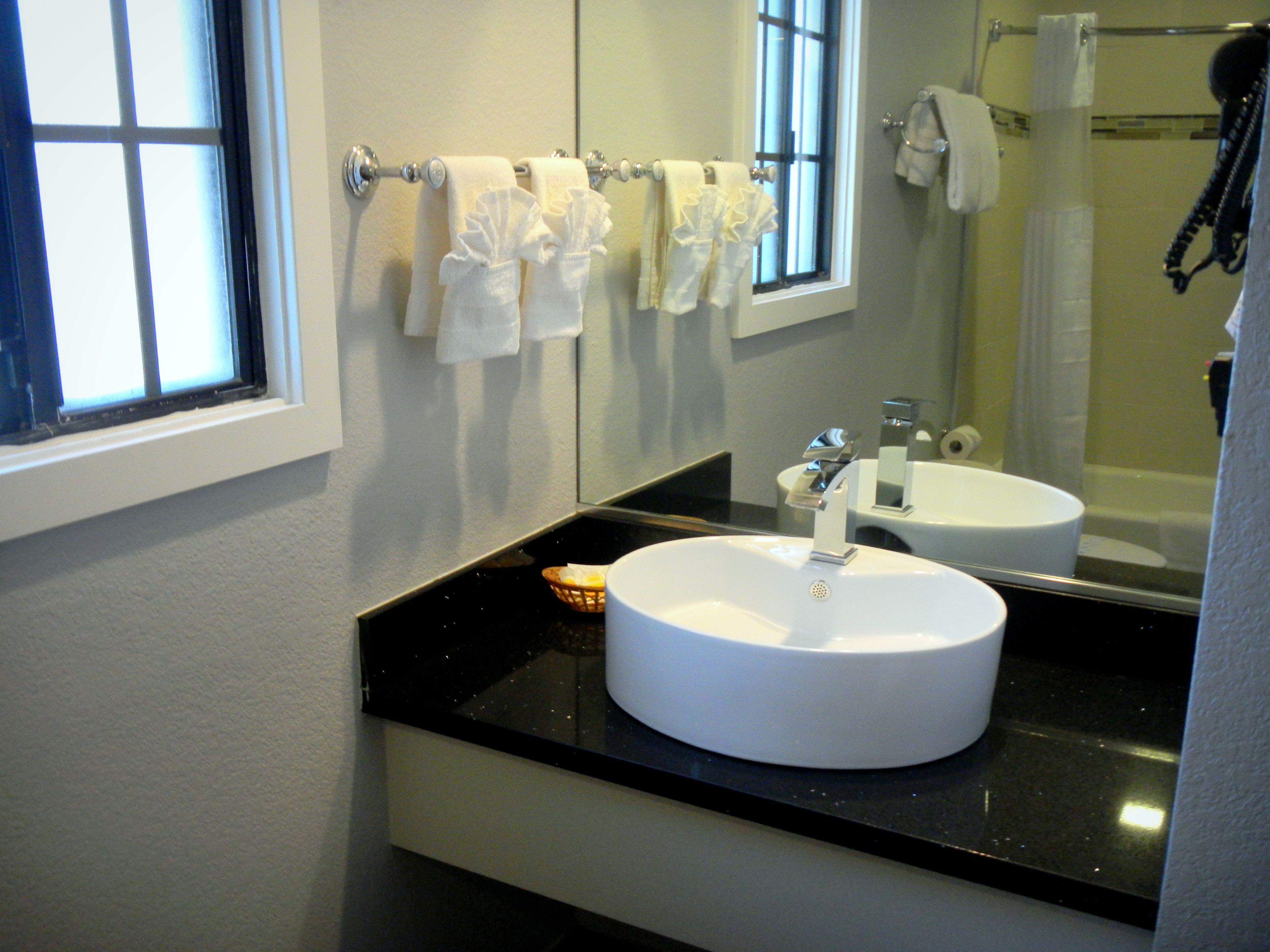 A bathroom with a white sink, a mirror, and a window.