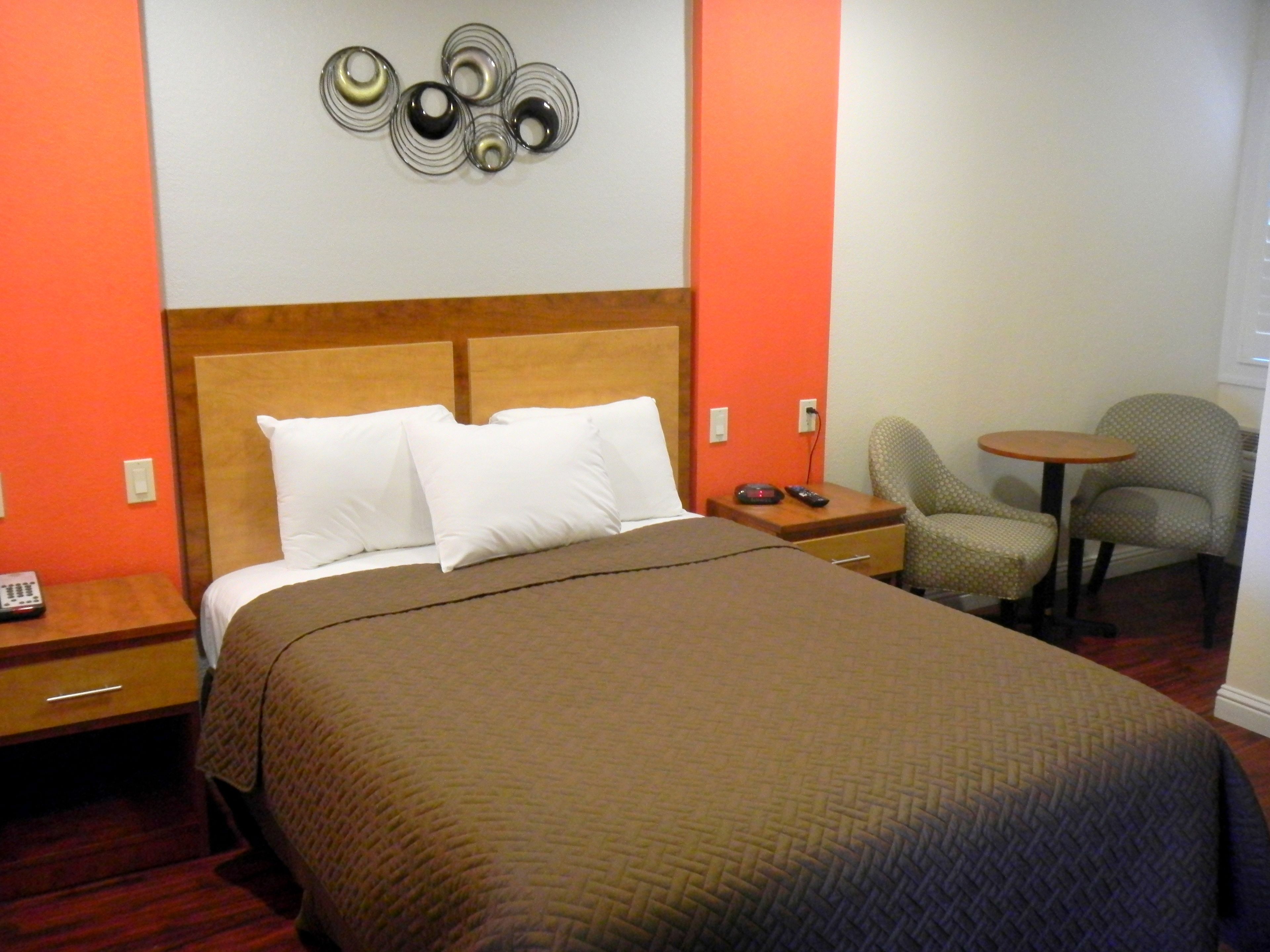 Una habitación de hotel con una cama grande, una mesita de noche, una silla y una pequeña mesa.