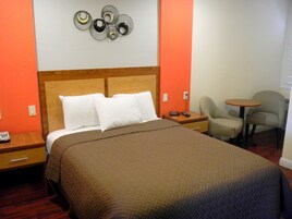 Una habitación de hotel con una cama grande, una mesita de noche, una silla y una pequeña mesa.
