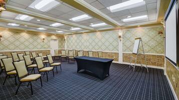 A conference room with a long table, multiple chairs, a whiteboard, and a carpeted floor.