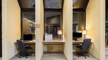 Un espacio de oficina moderno con dos escritorios, cada uno con una computadora y una lámpara.