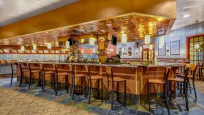 A bar area with a long counter, multiple stools, and a patterned carpet. - Wyndham Garden York (York)