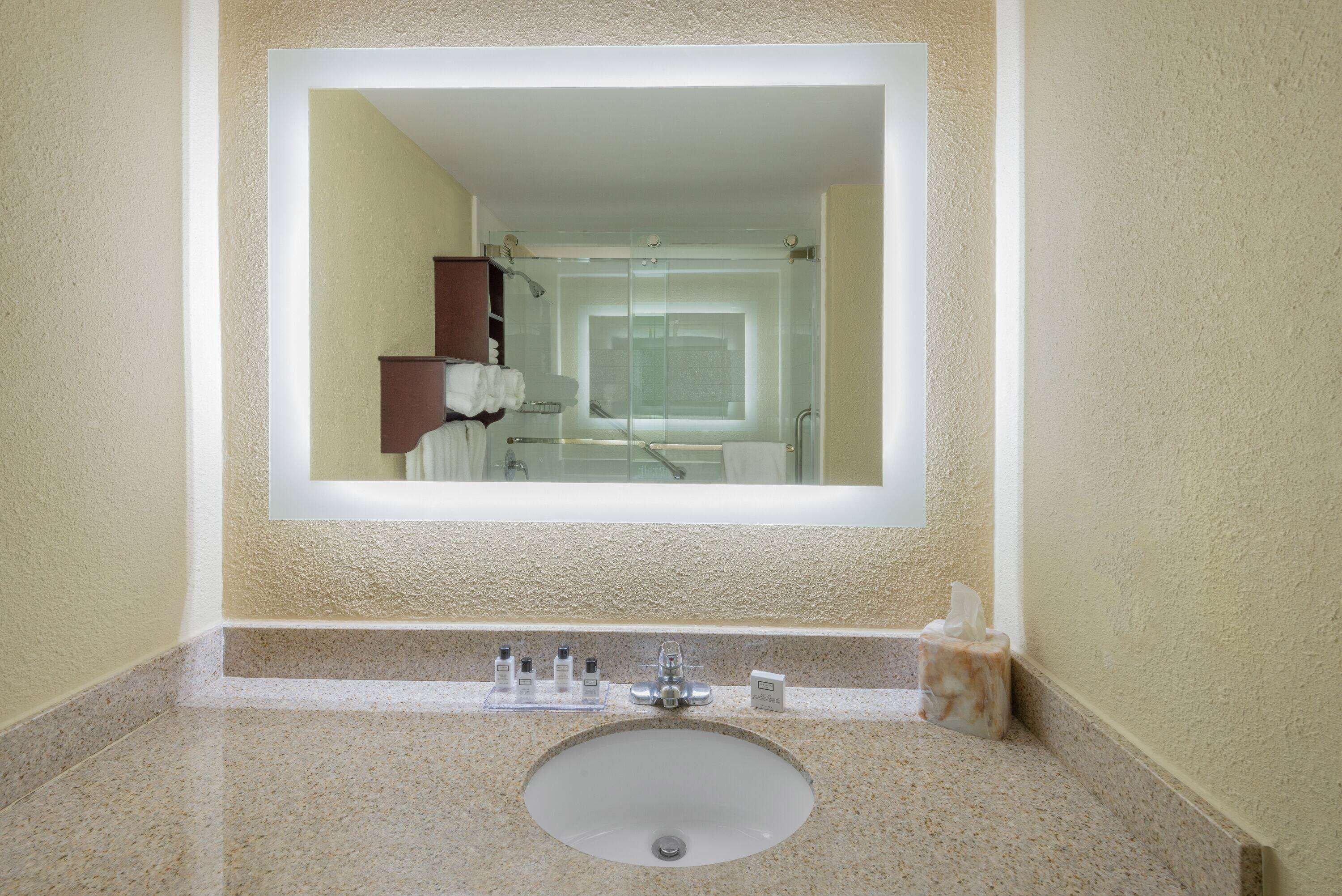 Ein Badezimmer mit Waschbecken, Spiegel und Pflegeprodukten.