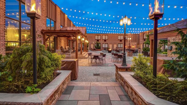 An outdoor patio with string lights, brick buildings, and outdoor seating. - Wyndham Garden York (York)