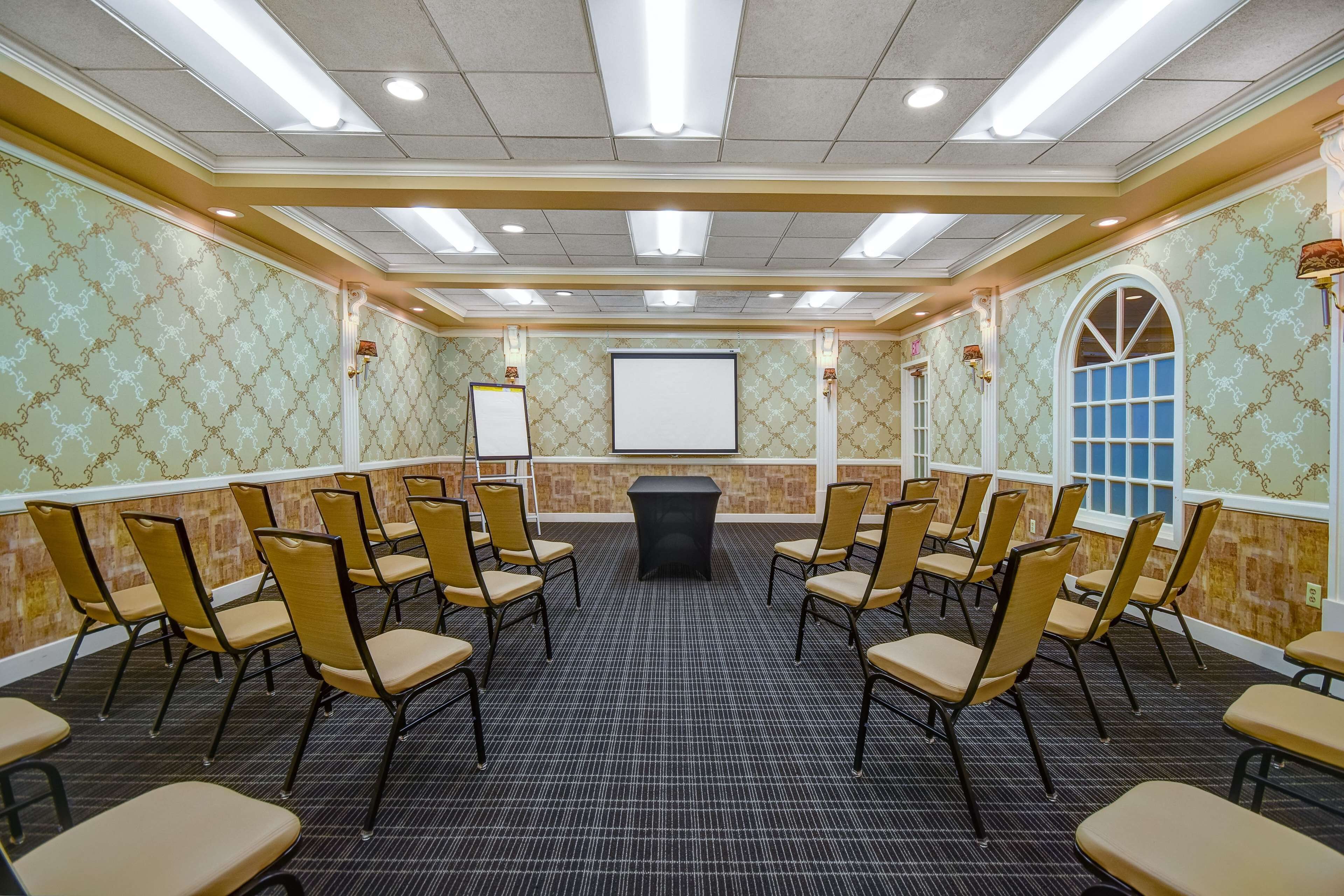 A conference room with a black table, beige chairs, patterned wallpaper, and a large window.