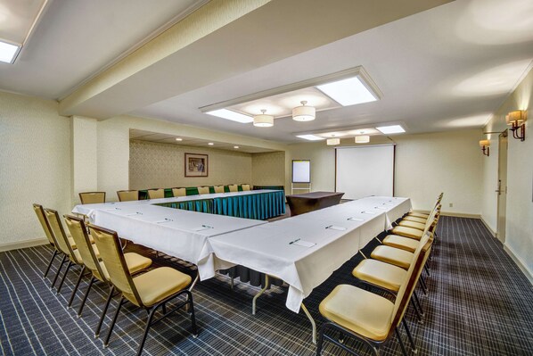 A conference room with a long table, chairs, a projector screen, and a whiteboard.