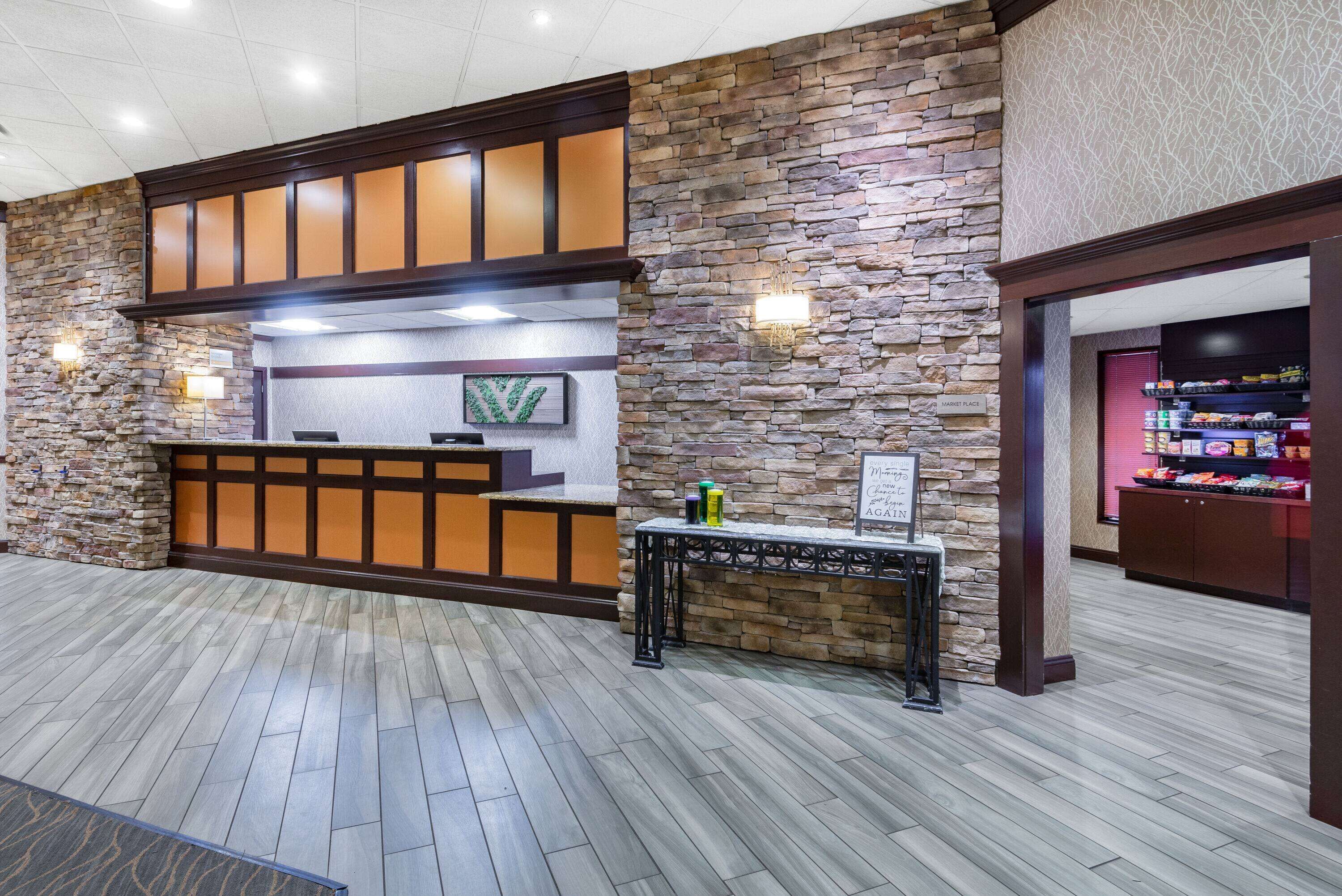A reception area with a stone wall, wooden reception desk, and a sign indicating a coffee shop.