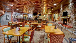 A cozy restaurant with wooden tables and chairs, a stone fireplace, and a bar area. - Wyndham Garden York (York)
