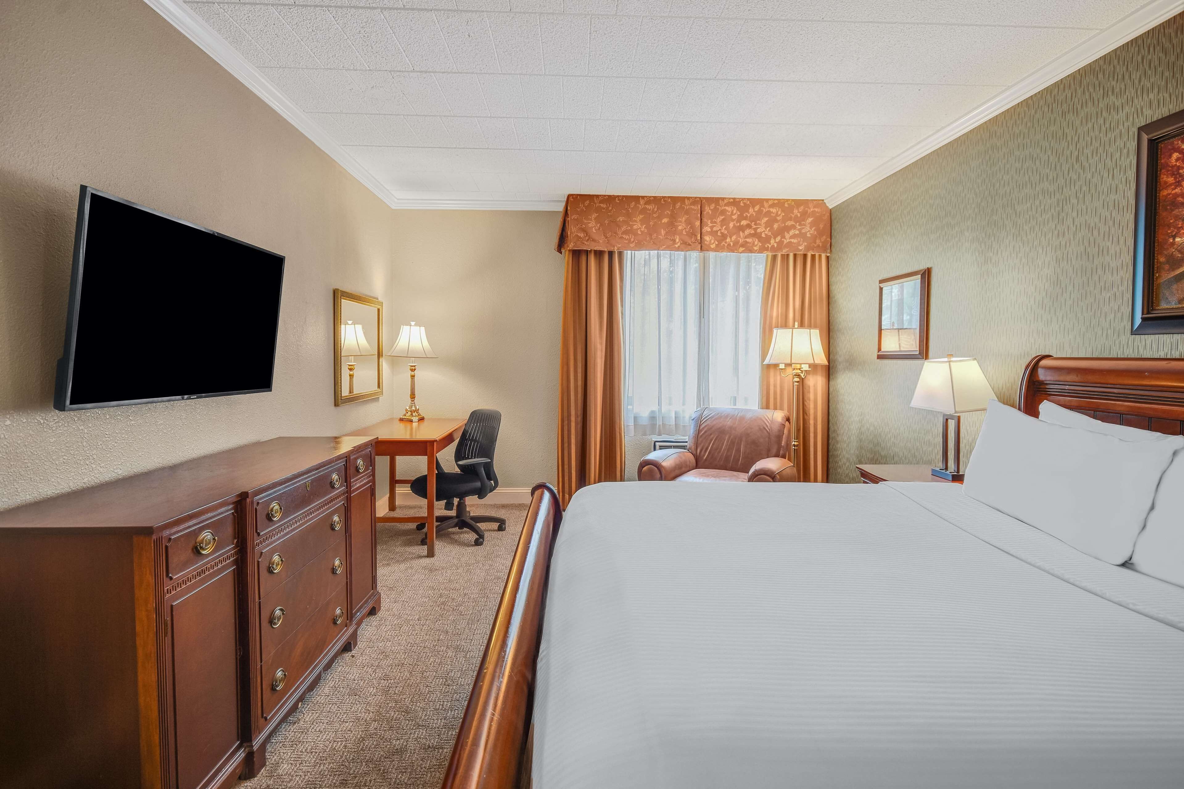 Habitación de hotel con una cama grande, un escritorio con una silla, un televisor y dos lámparas.