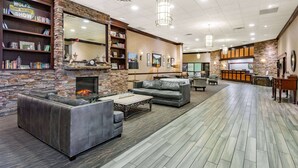 A spacious lobby with a stone fireplace, leather sofas, and a reception desk. - Wyndham Garden York (York)