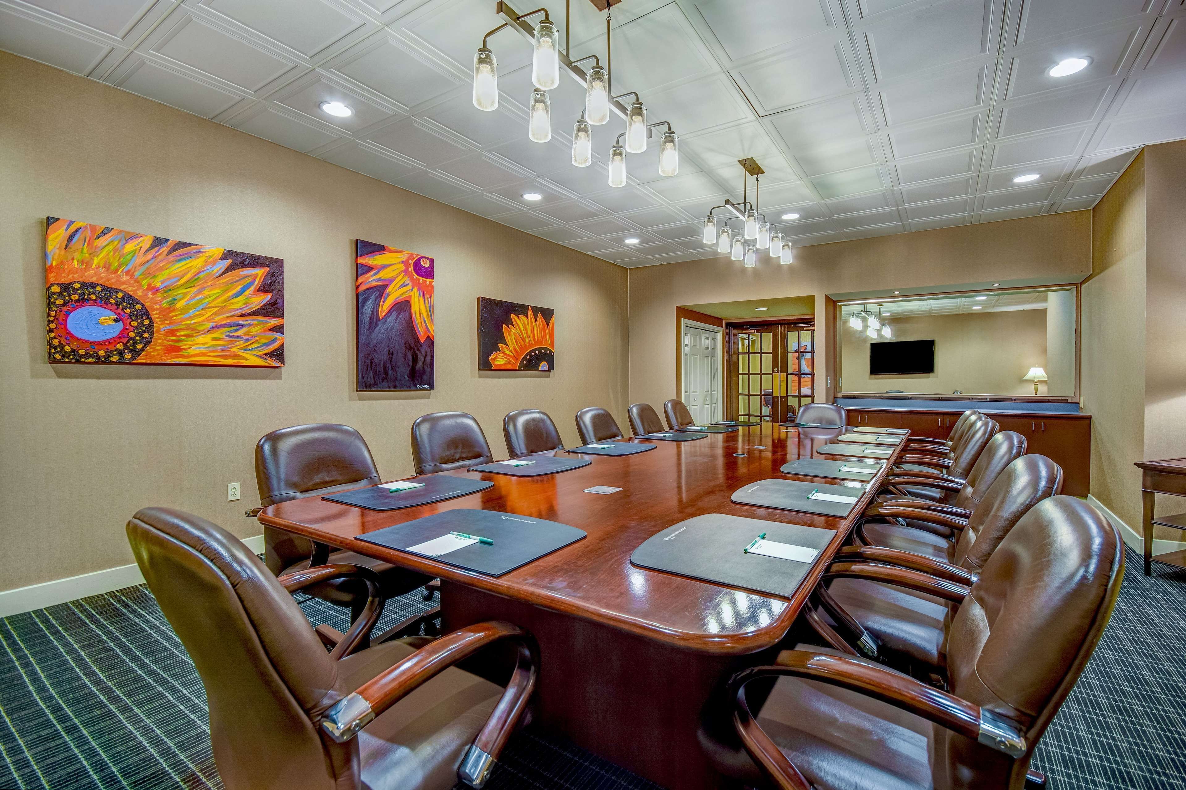 A conference room with a long table, leather chairs, and artwork on the walls.