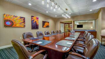 A conference room with a long table, leather chairs, and artwork on the walls.