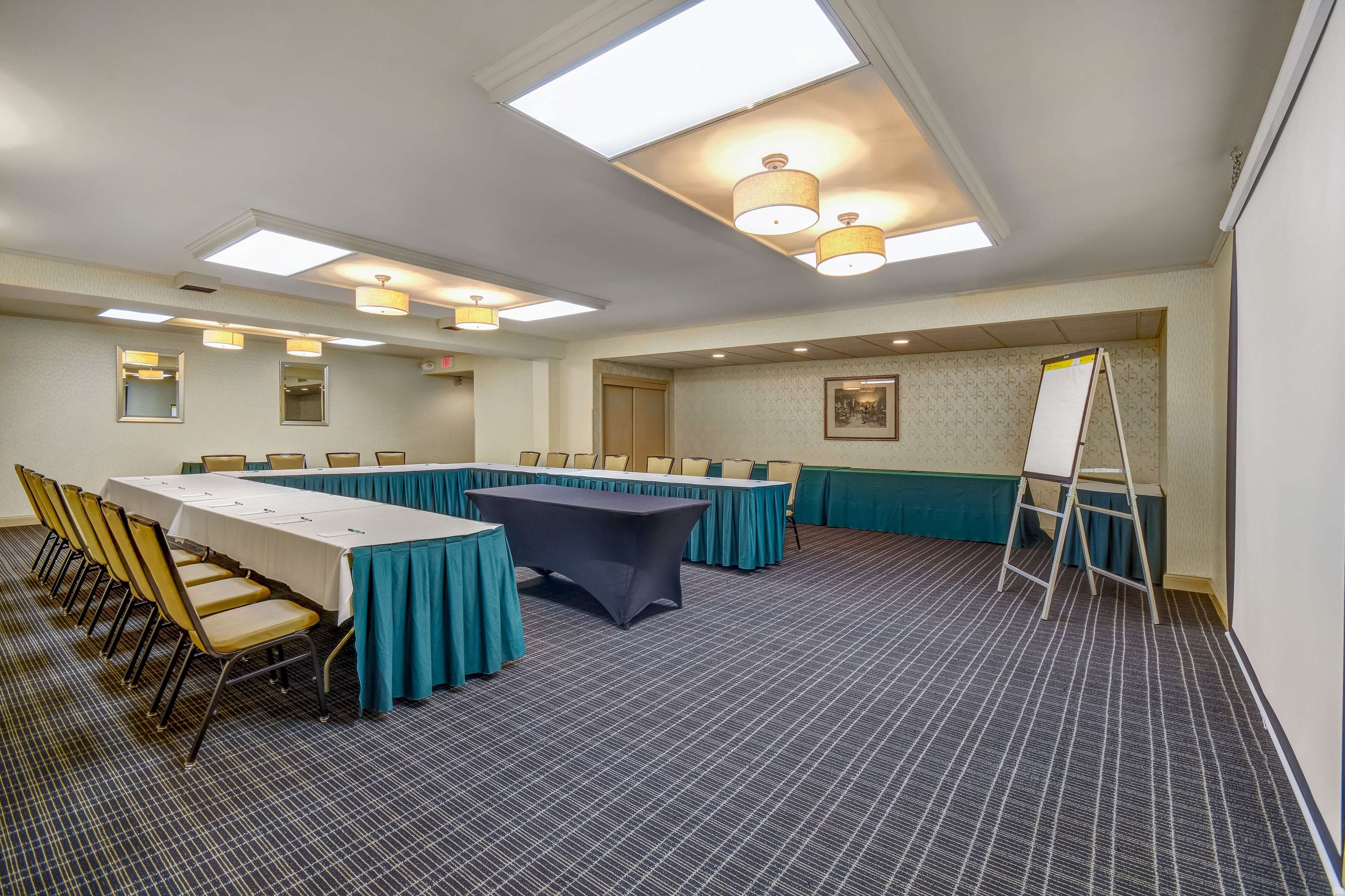 A conference room with a long table, chairs, and a whiteboard stand.