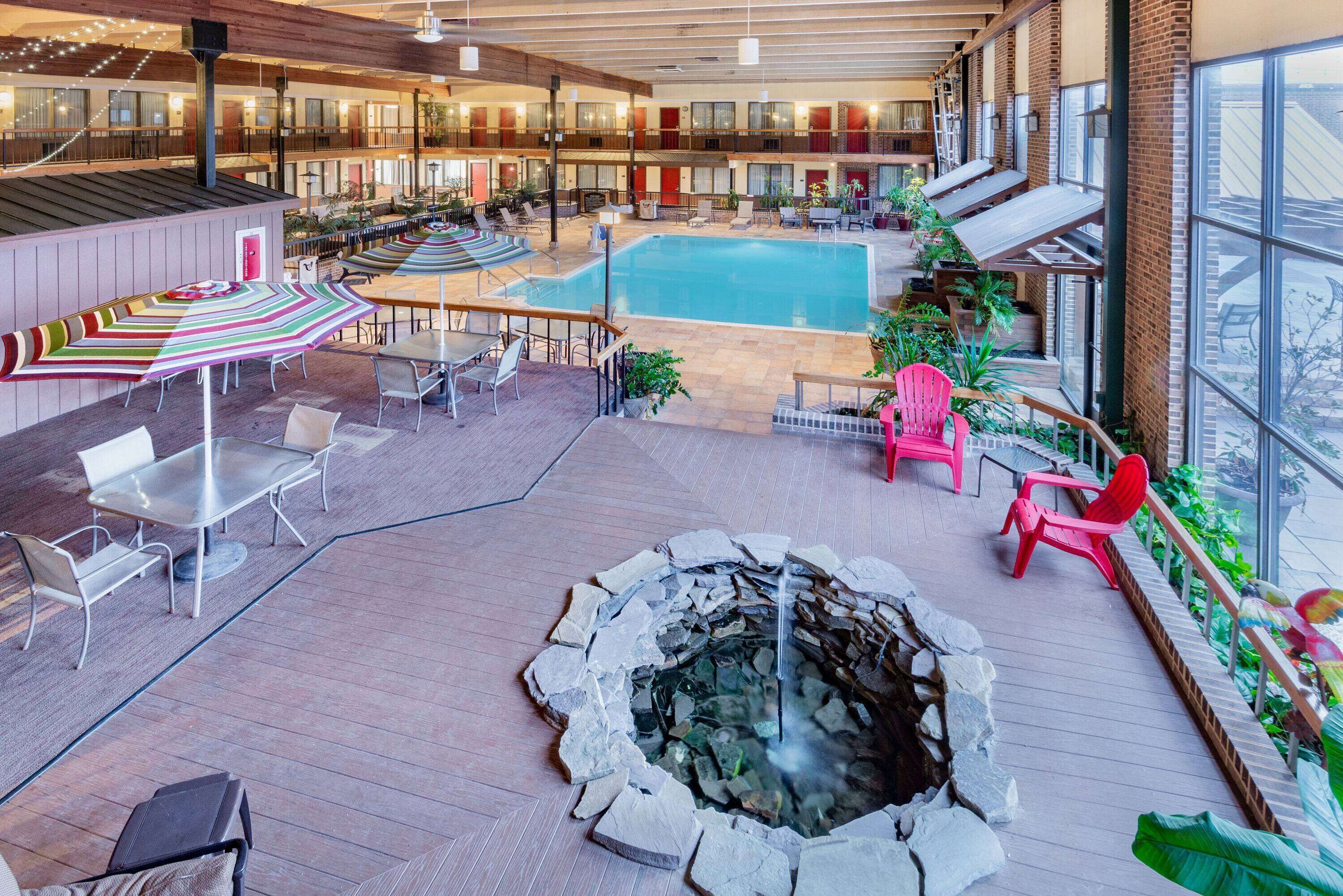 An indoor pool area with a hot tub, seating, and a view of the city.