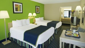 A hotel room with two beds, a desk with a tray of breakfast, a television, and two lamps.