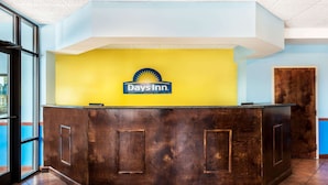 A reception desk with a Days Inn sign, a wooden counter, and a blue and yellow wall.