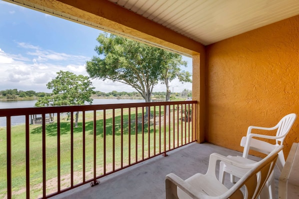 A balcony with a view of a lake and trees, featuring a concrete floor and a railing.