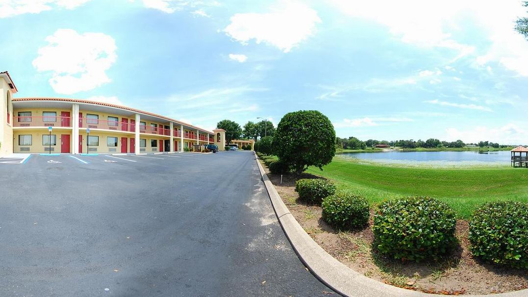 A motel with a parking lot, a large lawn, and a lake in the background.