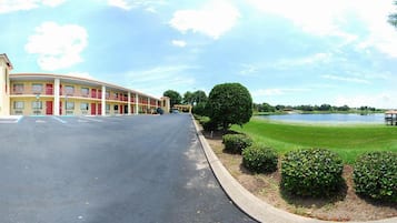 A motel with a parking lot, a large lawn, and a lake in the background.
