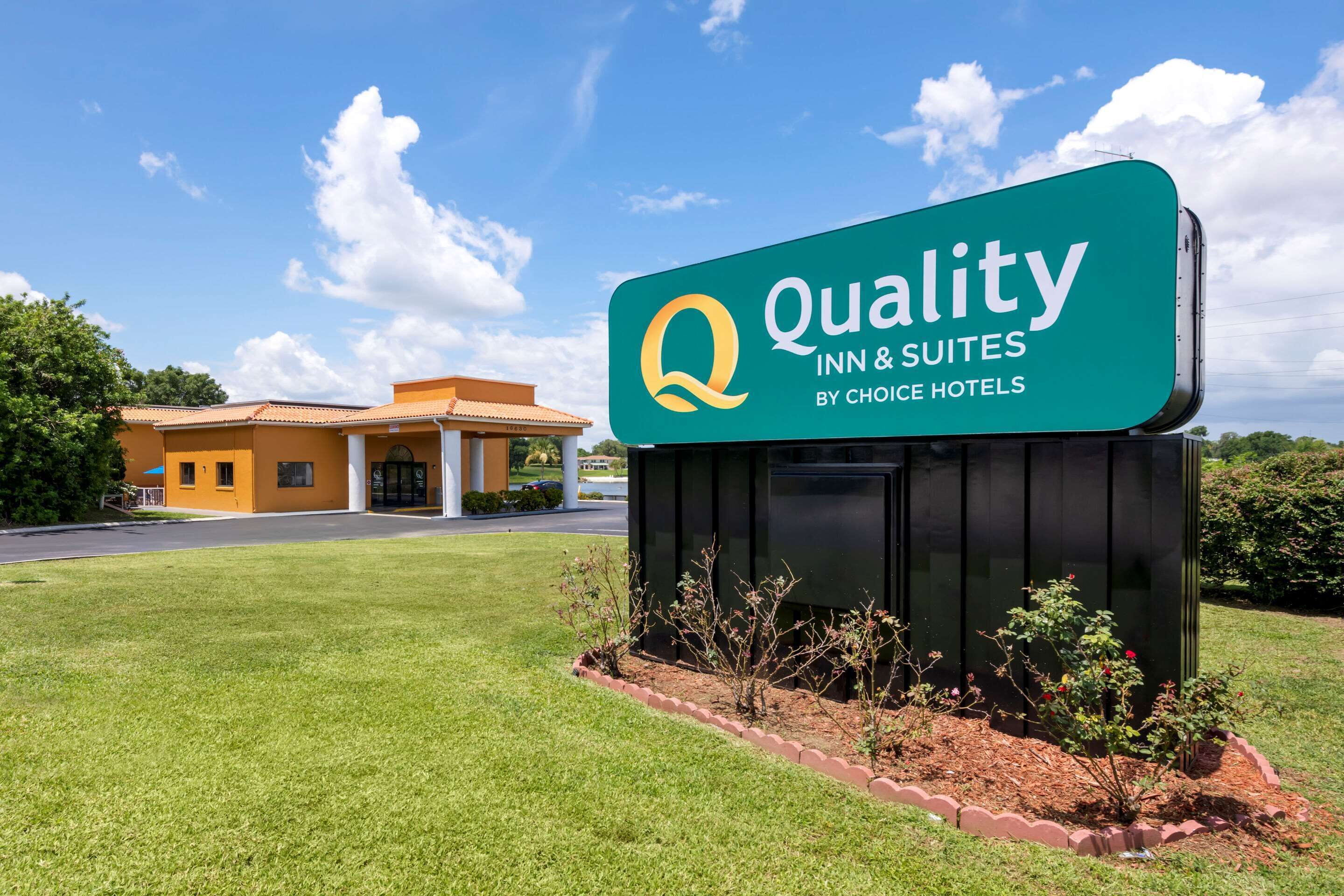 A sign for Quality Inn & Suites by Choice Hotels with a clear view of the building in the background.