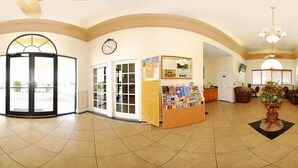 A spacious lobby with a reception desk, a clock, and a dining area. - Quality Inn & Suites Mt Dora North (Mount Dora)