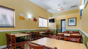 A dining area with multiple tables and chairs, a ceiling fan, and a television on the wall. - Quality Inn & Suites Mt Dora North (Mount Dora)