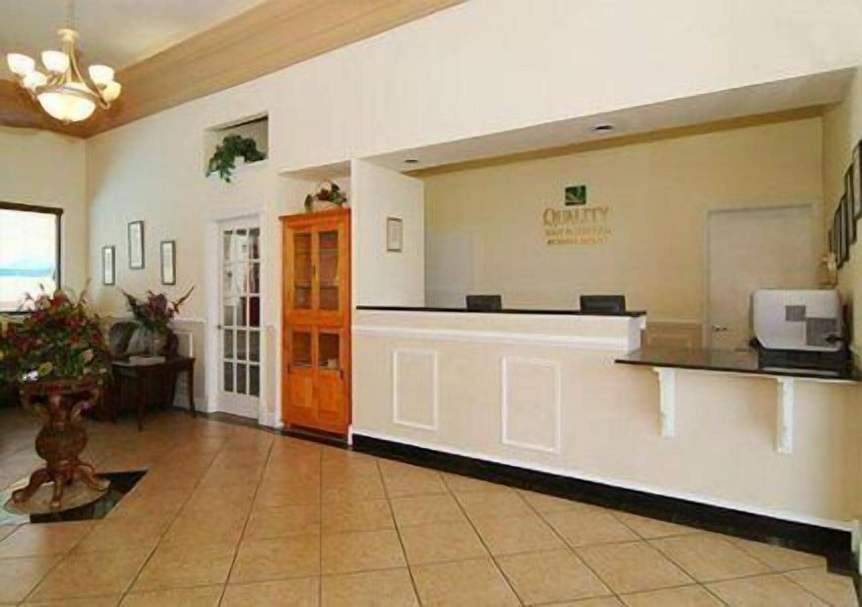 A reception area with a reception desk, a wooden door, and a plant.