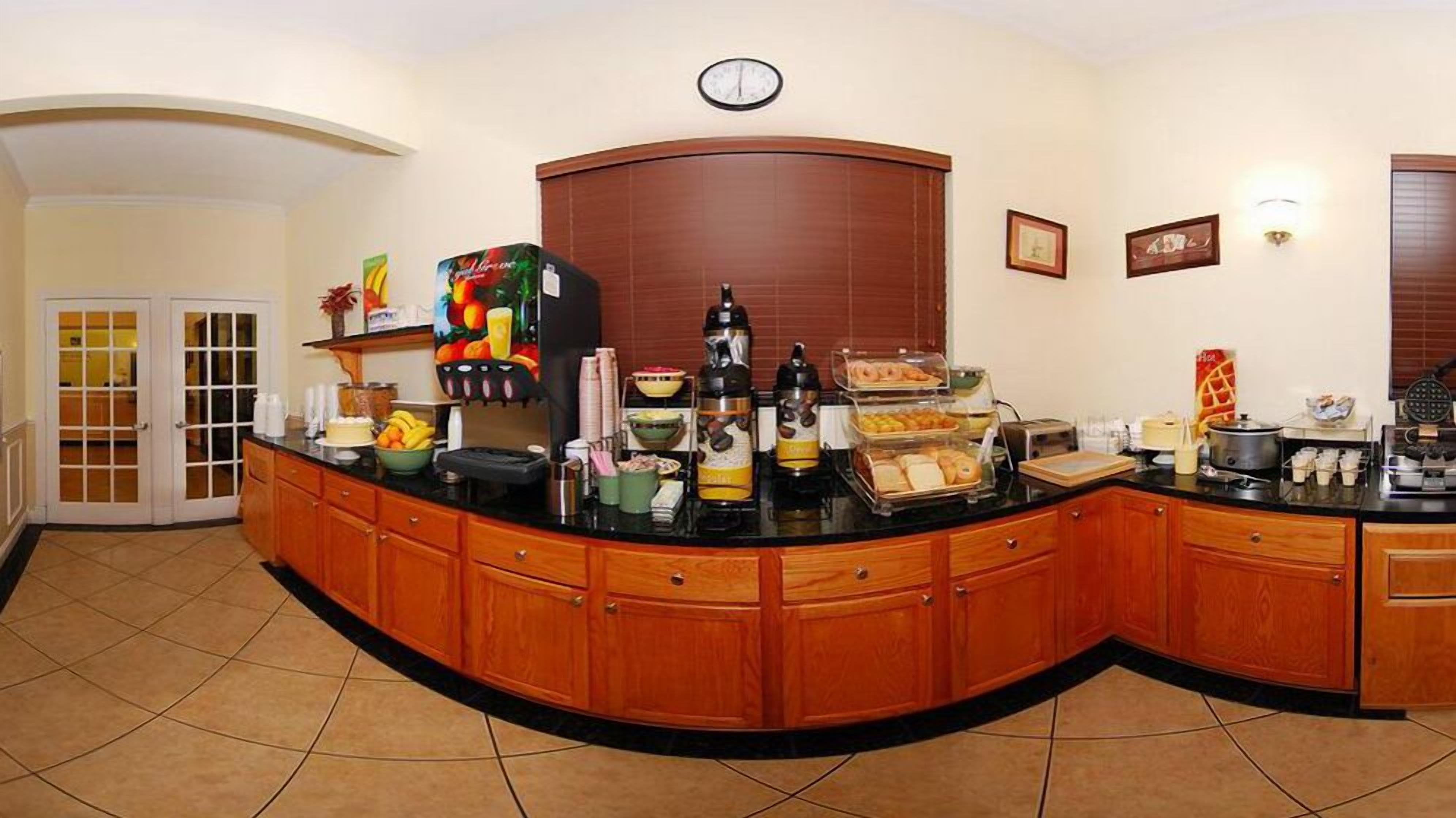 Una colazione a buffet con diversi cibi e bevande, un orologio appeso al muro e una porta che dà su un'altra stanza.