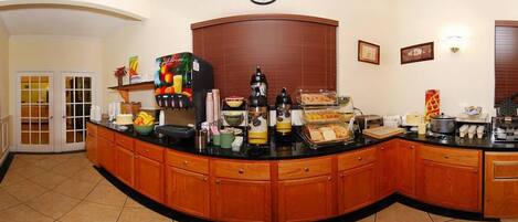 Una colazione a buffet con diversi cibi e bevande, un orologio appeso al muro e una porta che dà su un'altra stanza.