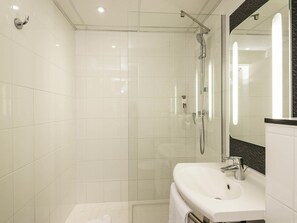 Une salle de bain moderne avec une douche à parois de verre, un lavabo blanc et un grand miroir.