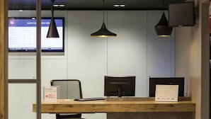 En receptionsdisk med en computer, et skilt til hurtig udtjekning og en skærm, der viser hotellets serviceoversigt.