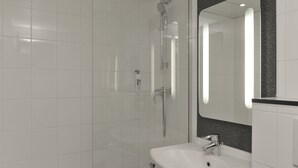 Une salle de bain moderne avec une douche en verre, un lavabo blanc et un grand miroir agrémenté d’un pare-splash foncé.