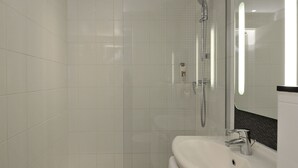 Une salle de bain moderne avec une douche à parois de verre, un lavabo blanc et un miroir avec un cadre noir.