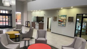 A modern lobby with seating areas, a reception desk, and artwork on the walls.