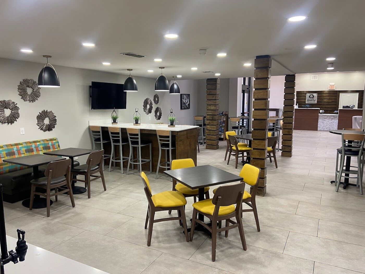 A restaurant with a bar area, multiple tables and chairs, and a counter with a sign that says "Quality".
