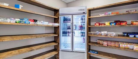 A modern hotel pantry with wooden shelves stocked with snacks and beverages.