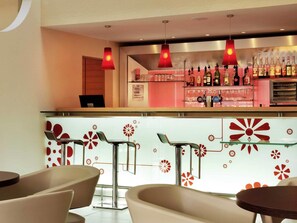 A bar area with a counter, bar stools, and a selection of liquor bottles.
