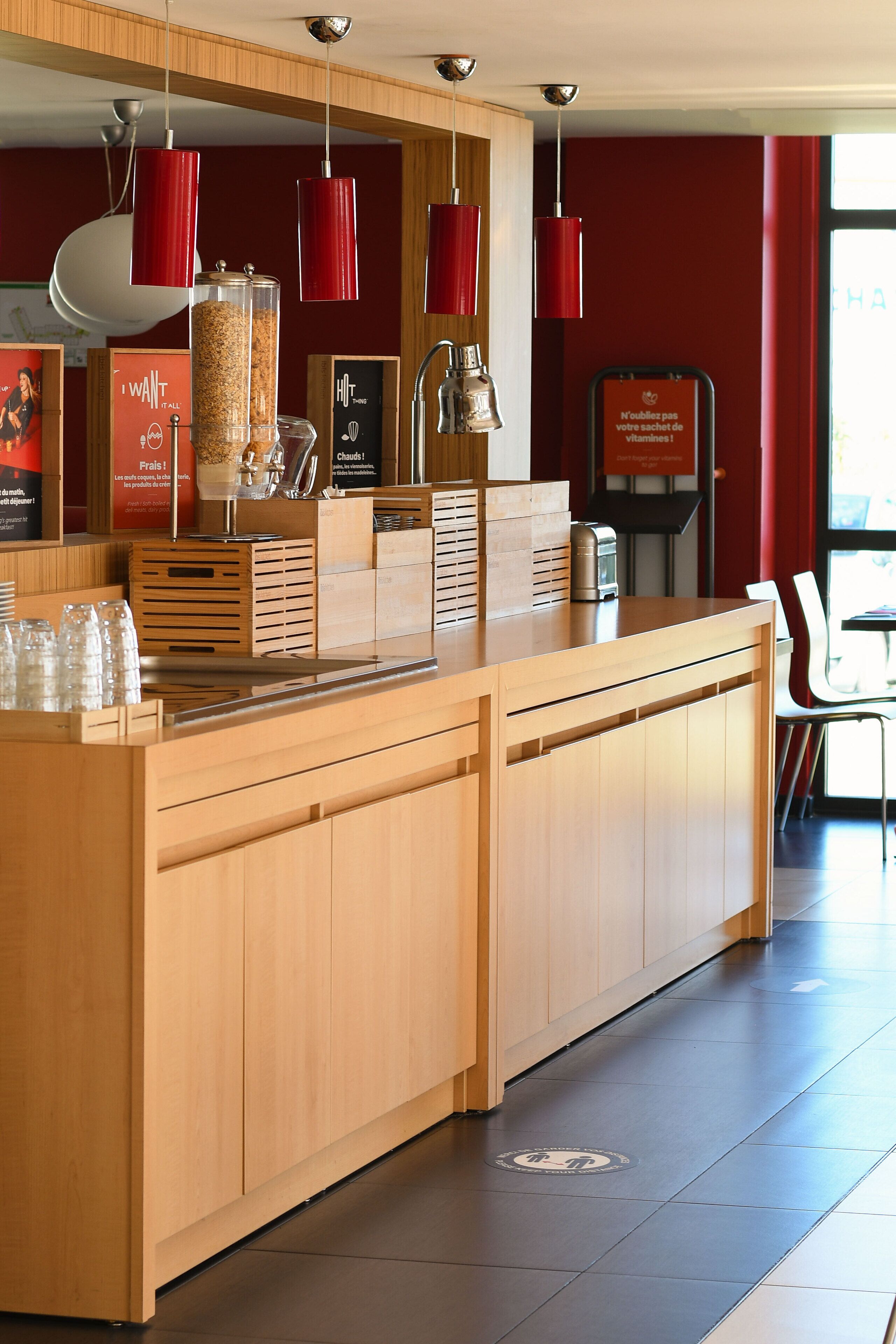 A modern reception area with wooden counters, red pendant lights, and a glass display case.