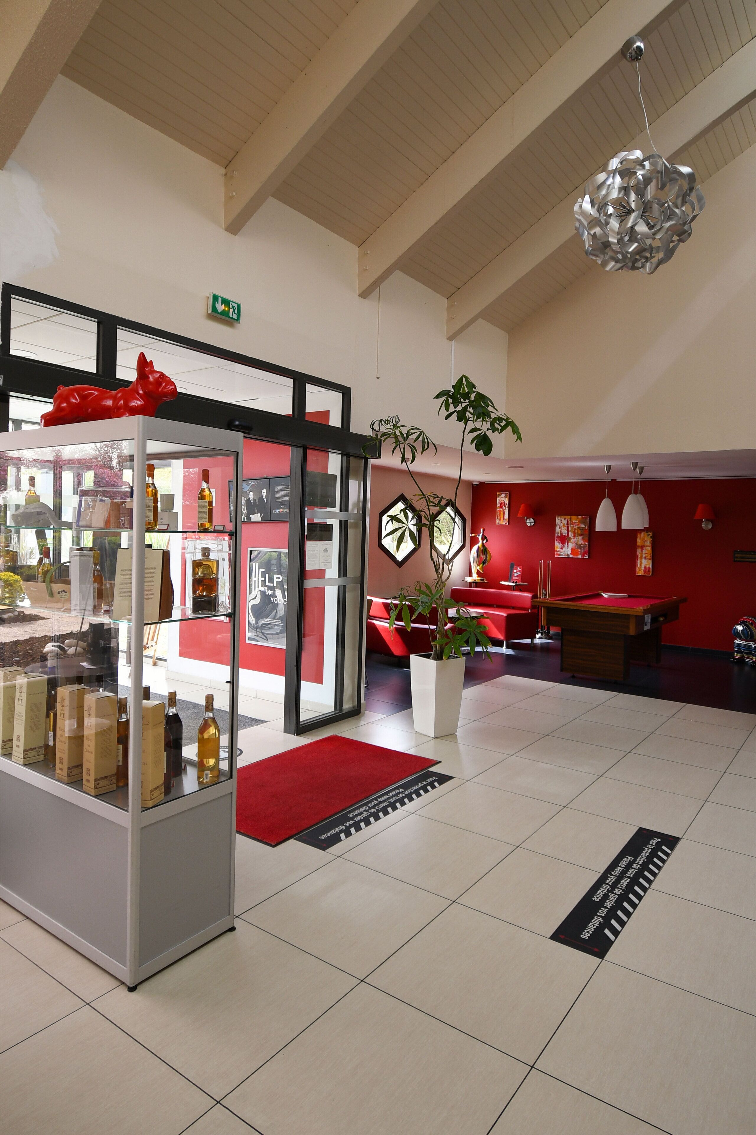 A lobby with a glass display case, red walls, a pool table, and a potted plant.