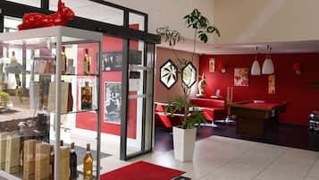 A lobby with a glass display case, red walls, a pool table, and a potted plant.