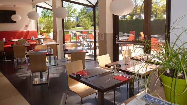 Un área de comedor interior con mesas, sillas y una planta en maceta.