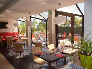 An indoor dining area with tables, chairs, and a potted plant.